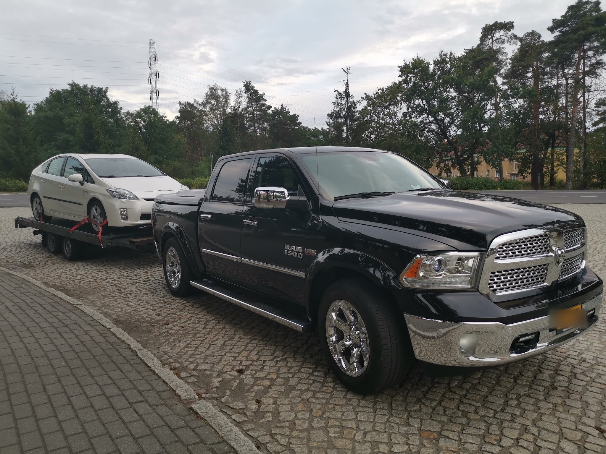 De zwarte pick-up van Garage Sieniol met een witte auto op de autotransportaanhanger